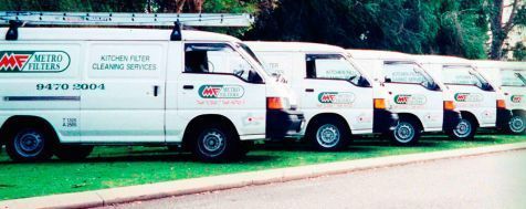 A line of white service vans for Metro Filters kitchen filter cleaning services