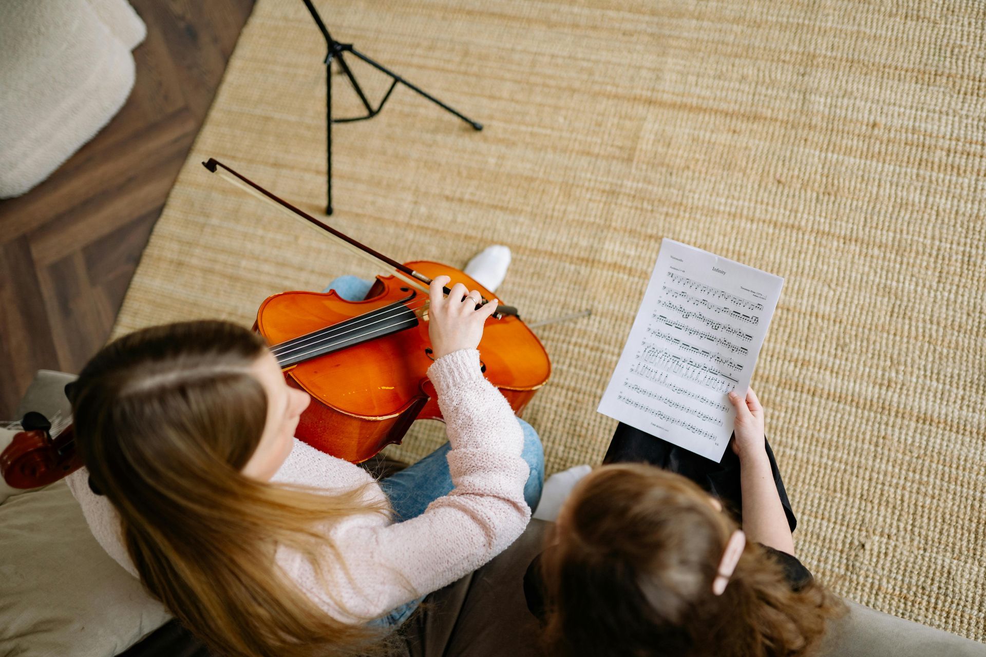 A woman is teaching a young girl how to play the violin.