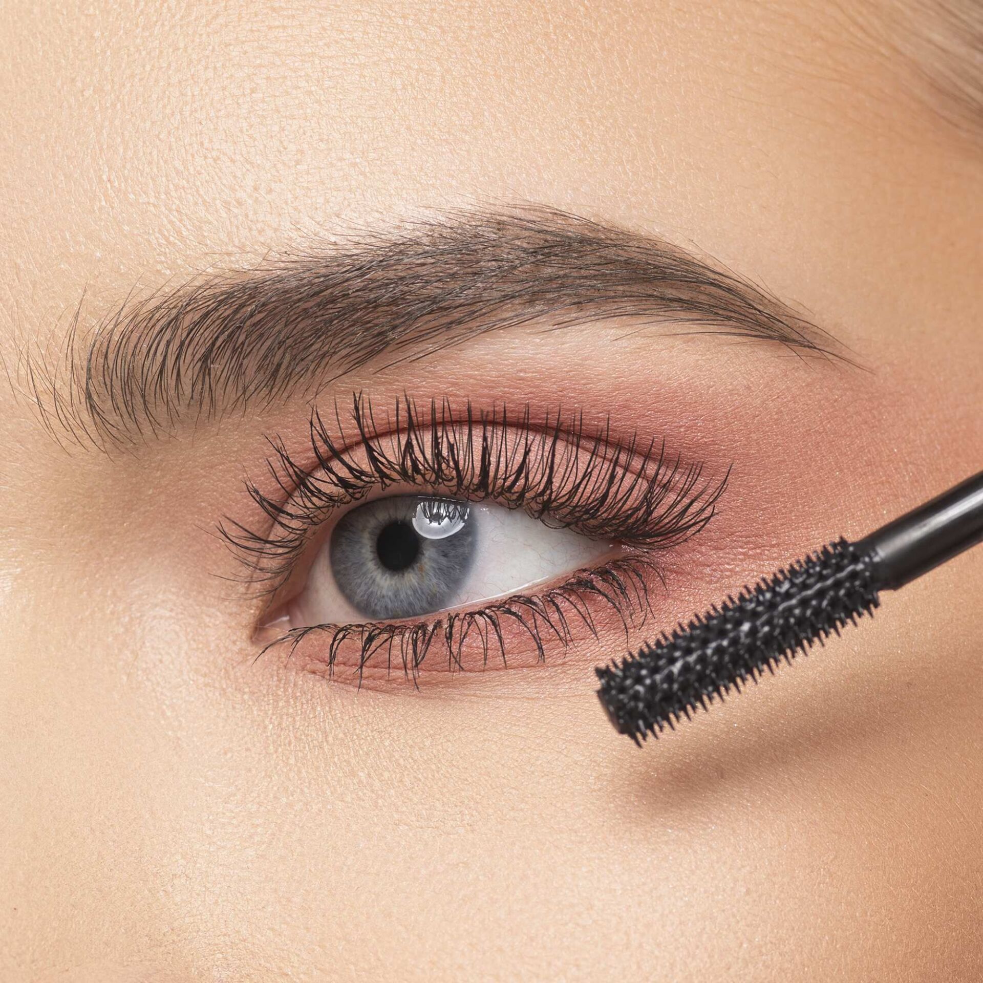 Una donna si sta applicando il mascara sugli occhi.