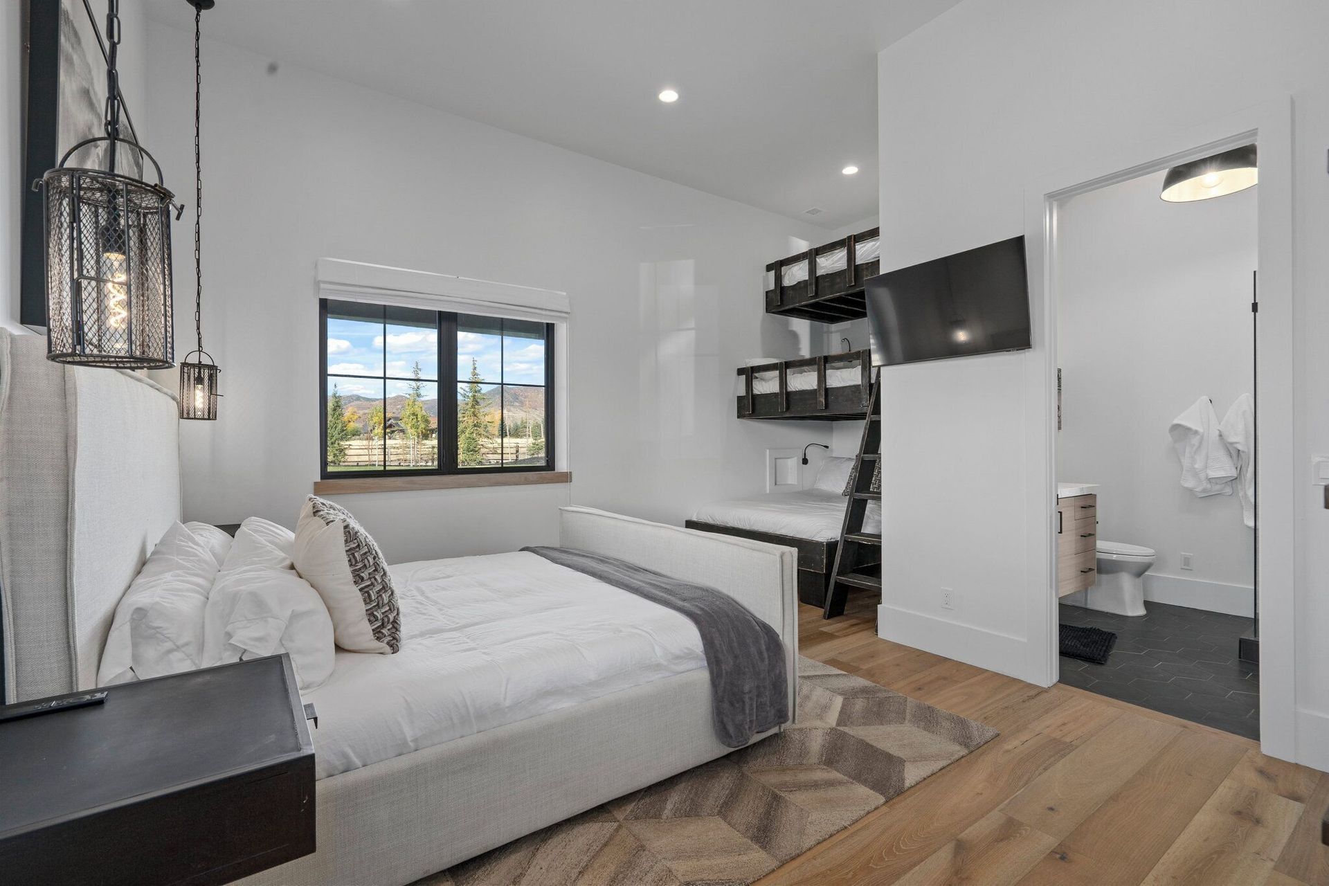 Bedroom with bunk beds, large bed, and en suite bathroom; neutral tones, modern style.