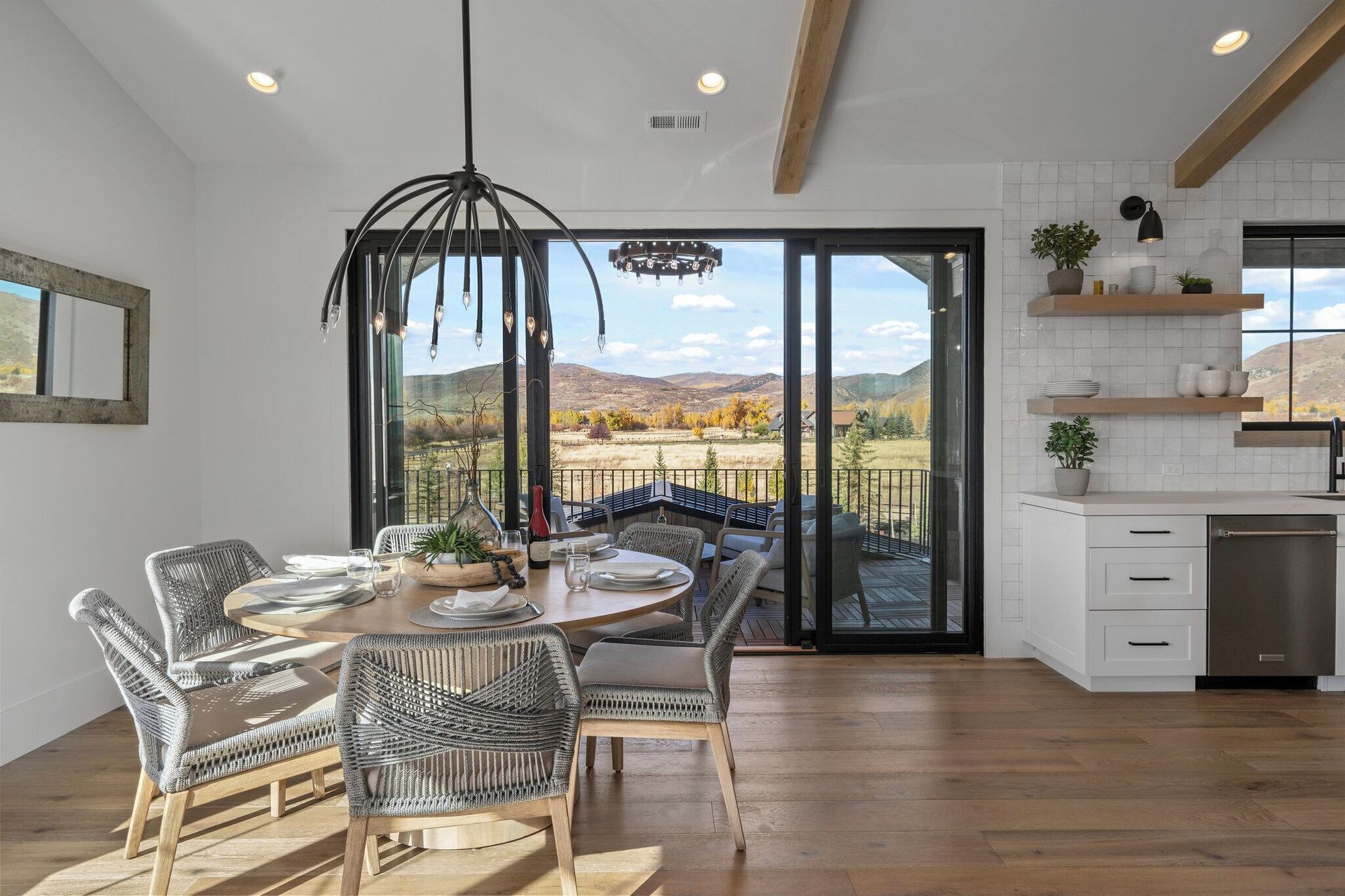 Dining room with sliding glass doors, mountain view, round table with chairs, modern light fixture.