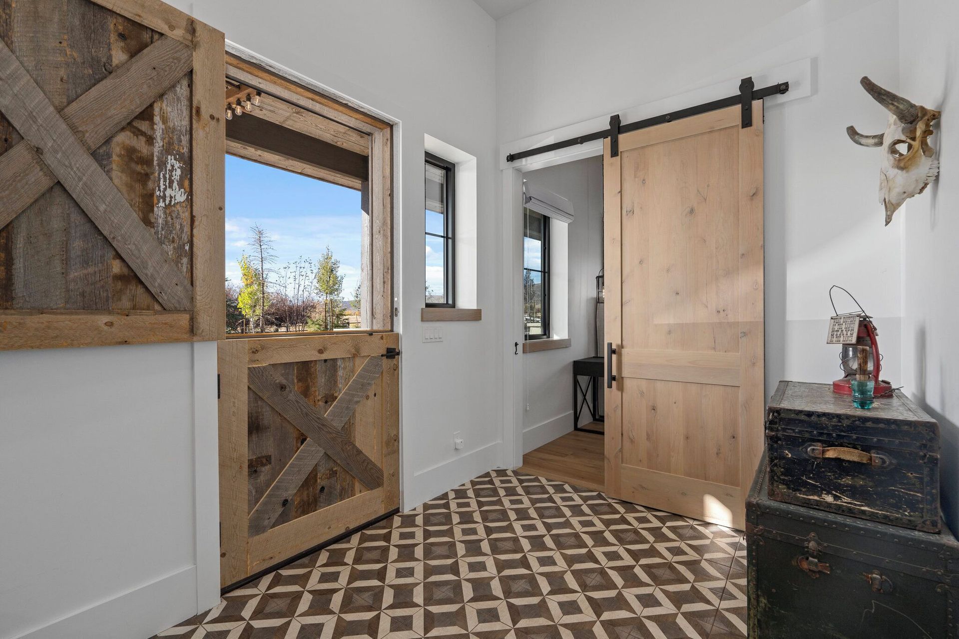 Rustic entryway with barn doors, patterned tile floor, and decorative chest.