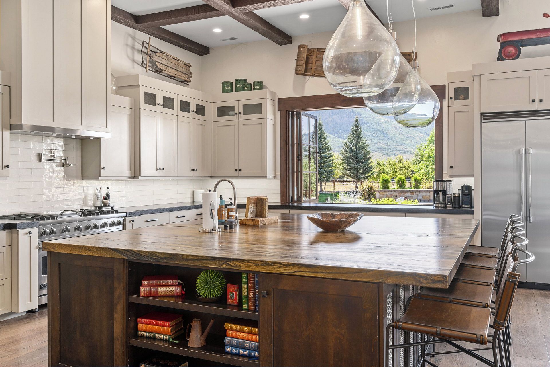 Kitchen with dark wood island, cabinets, stainless steel appliances, and a view of a green landscape.