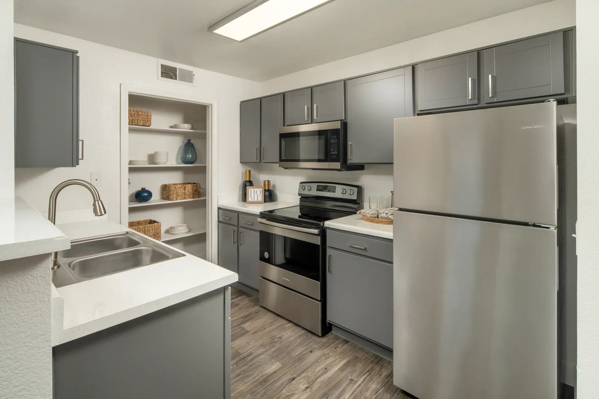 Modern kitchen with stainless steel appliances, grey cabinets, and a double sink at Heritage at Deer Valley in Phoenix, AZ.