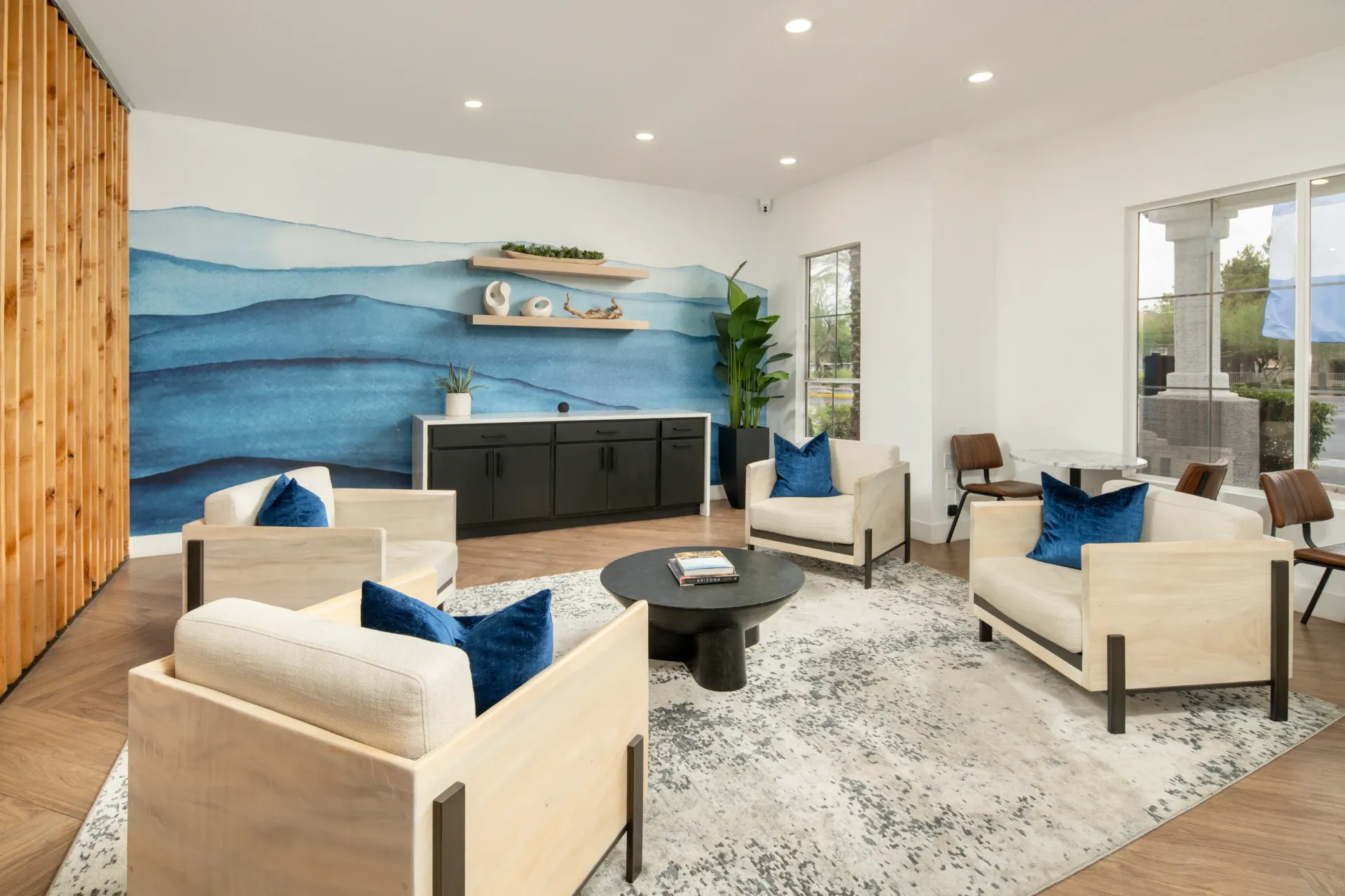 Modern lounge area with comfortable seating and abstract blue wave mural.