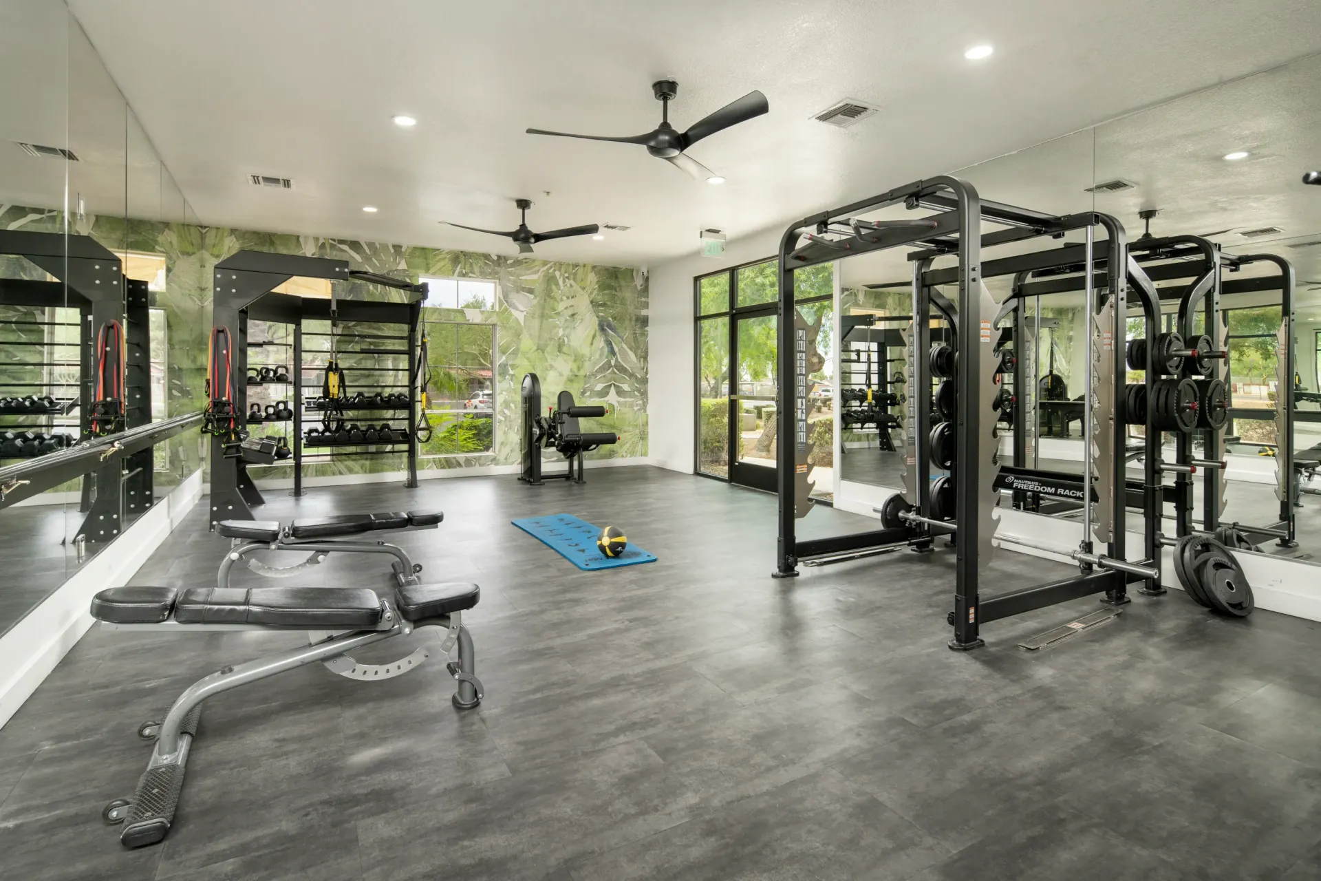 Fully equipped gym with weight machines, free weights, benches, and yoga mat at Heritage at Deer Valley in Phoenix, AZ.