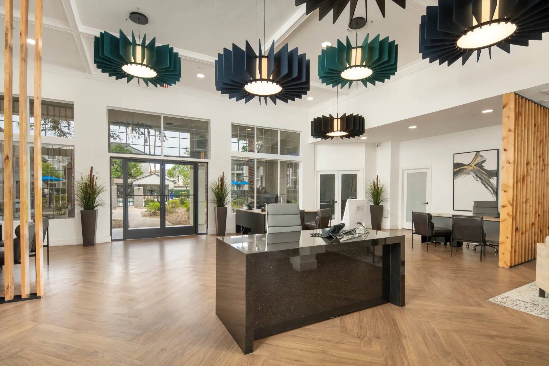 Modern leasing office with a dark granite reception desk, stylish pendant lights, and large windows at Heritage at Deer Valley in Phoenix, AZ.