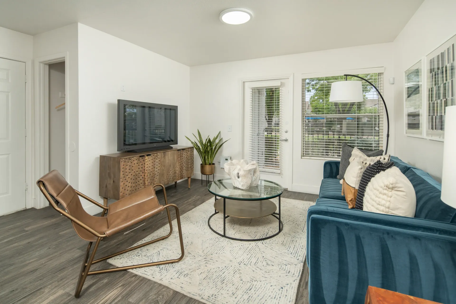 Modern living room with a teal sofa, leather chair, and TV.
