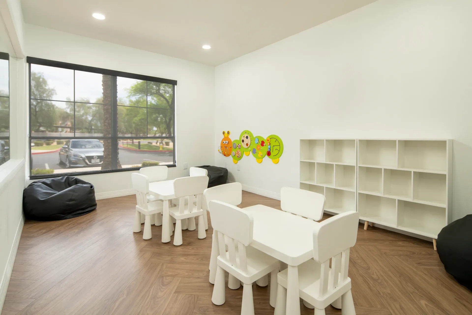 Children's play area with small tables and chairs, bean bag chairs, and shelves at Heritage at Deer Valley in Phoenix, AZ.