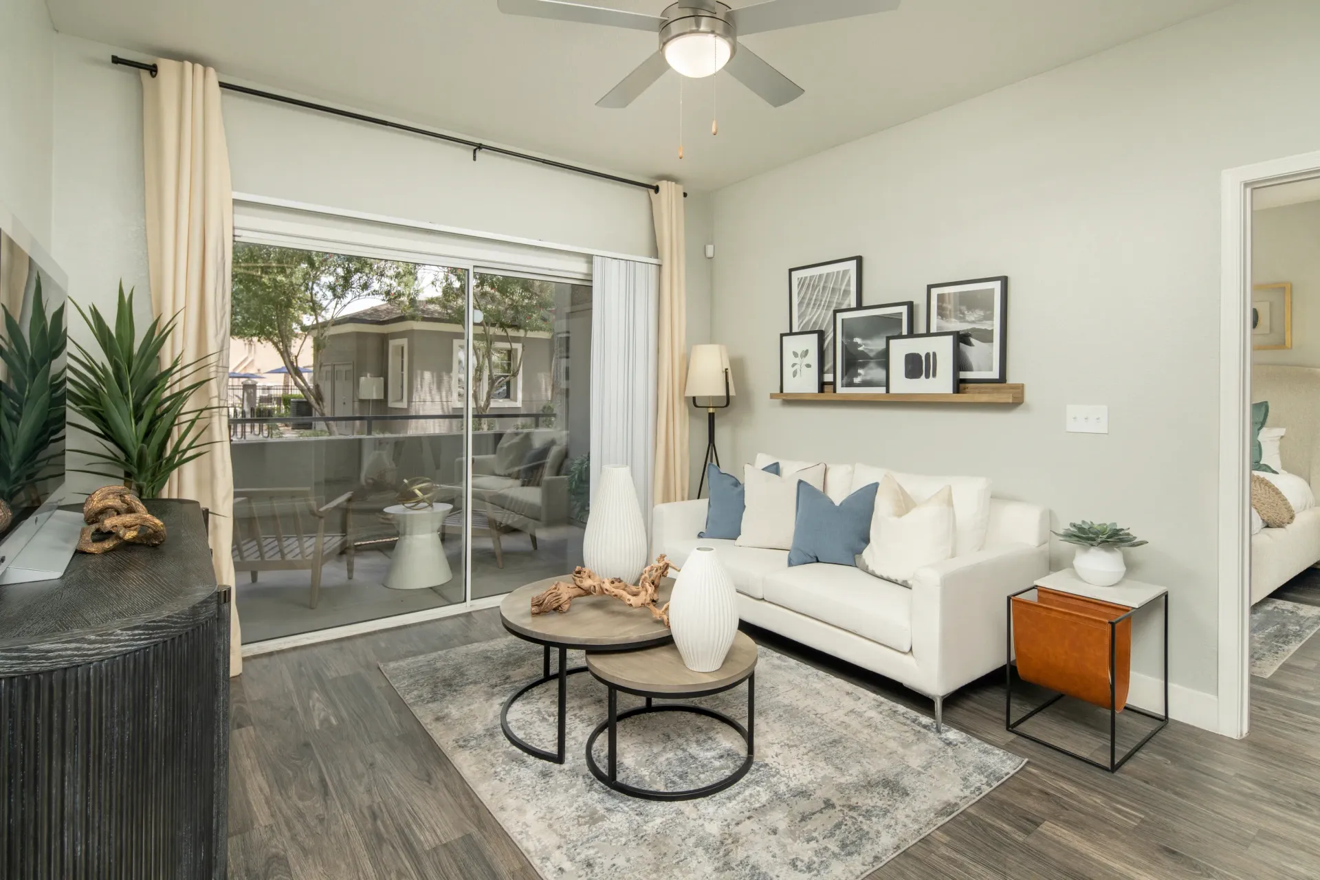 Living room with white sofa, coffee tables, and patio access at Heritage at Deer Valley in Phoenix, AZ.