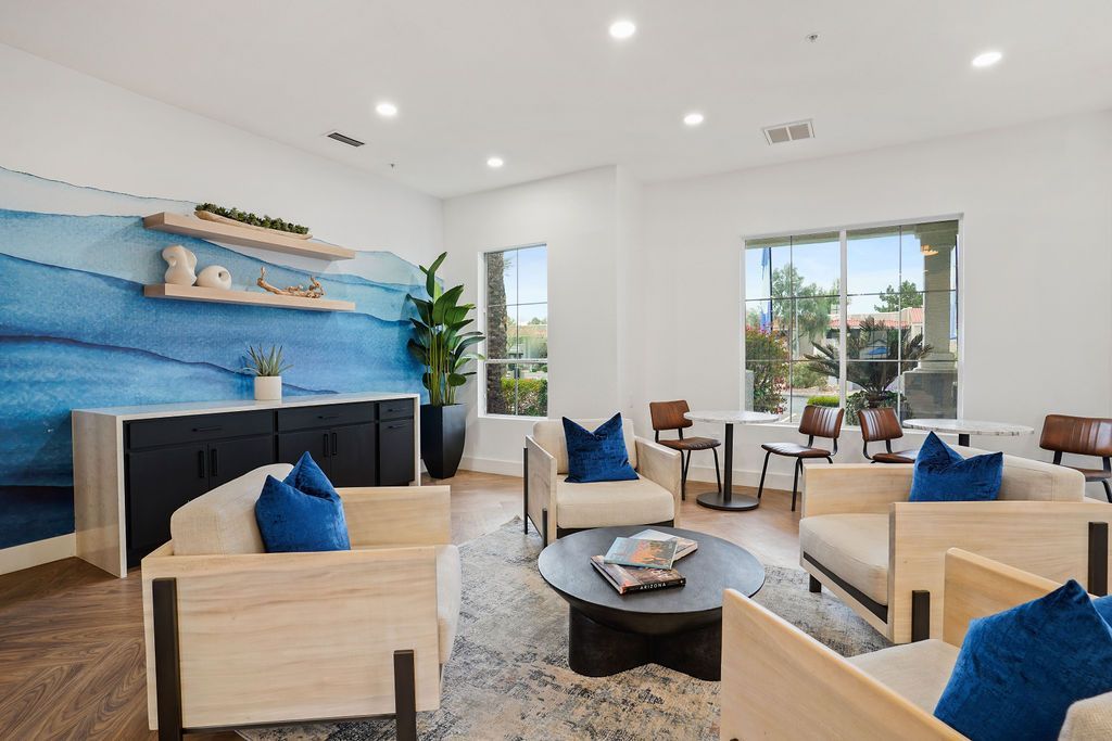 Interior community lounge with blue wave mural, beige seating, and large windows at Heritage at Deer Valley in Phoenix, AZ.