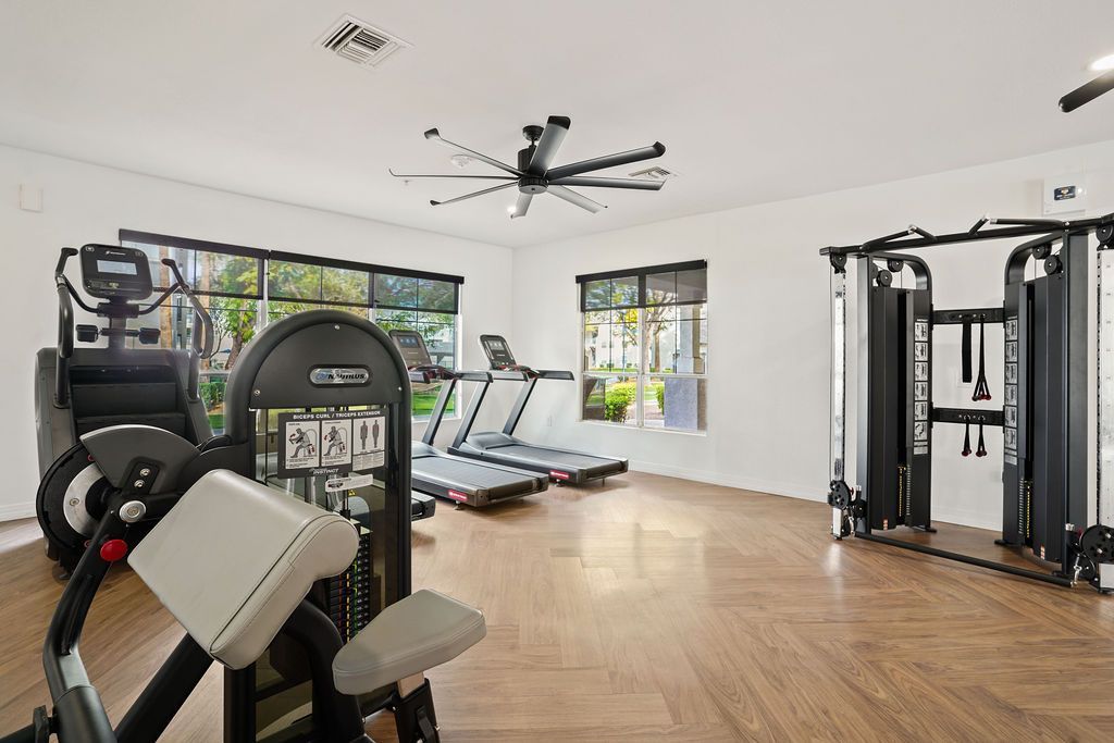 Well-lit community gym with treadmills, cardio machines, and a multi-station weight/cable tower at Heritage at Deer Valley in Phoenix, AZ.