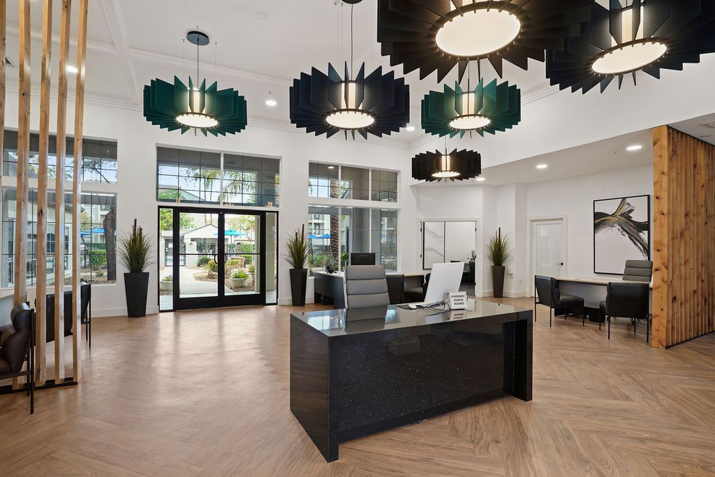 Modern apartment community lobby with a reception desk, seating, and large windows at Heritage at Deer Valley in Phoenix, AZ.