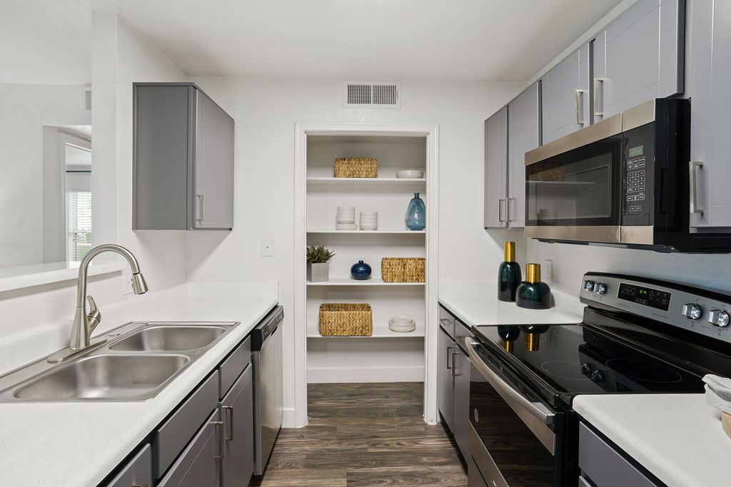 Modern apartment kitchen with a double sink, stainless appliances, and open pantry shelves at Heritage at Deer Valley in Phoenix, AZ.