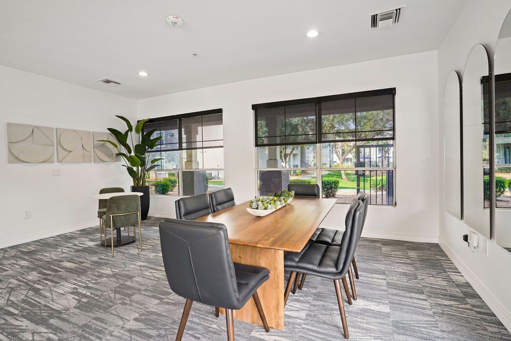 Bright communal meeting room with a wooden table, black chairs, and large windows at Heritage at Deer Valley in Phoenix, AZ.