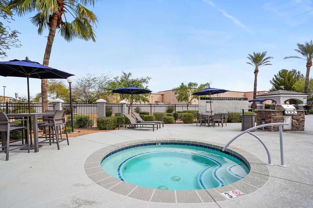 Outdoor community pool area with lounge chairs, tables, and umbrellas at Heritage at Deer Valley in Phoenix, AZ.