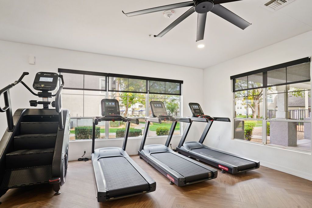 Indoor communal gym with treadmills and an elliptical by large windows at Heritage at Deer Valley in Phoenix, AZ.