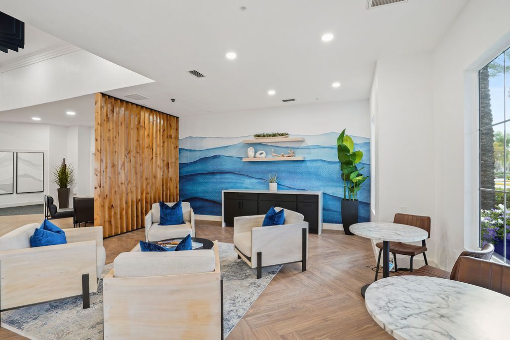 Indoor community lounge with a blue wave mural, seating and marble tables at Heritage at Deer Valley in Phoenix, AZ.
