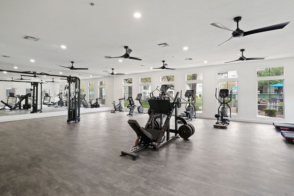 Bright community fitness center with cardio machines, free weights, and mirrors at Heritage at Deer Valley in Phoenix, AZ.