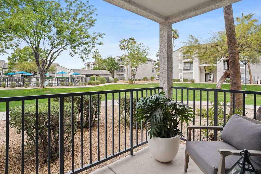 Balcony view with a potted plant and chair overlooking a landscaped community lawn and pool at Heritage at Deer Valley in Phoenix, AZ.