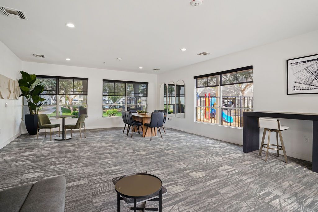 Bright communal lounge with windows, multiple seating areas, and a bar-height counter at Heritage at Deer Valley in Phoenix, AZ.