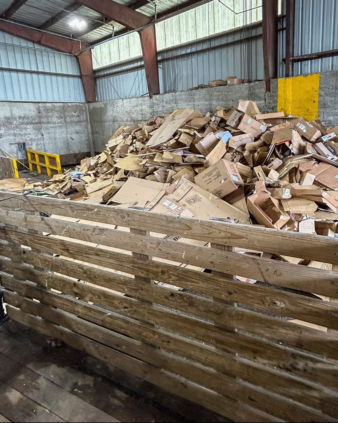 A pile of cardboard boxes in a wooden crate in a warehouse.