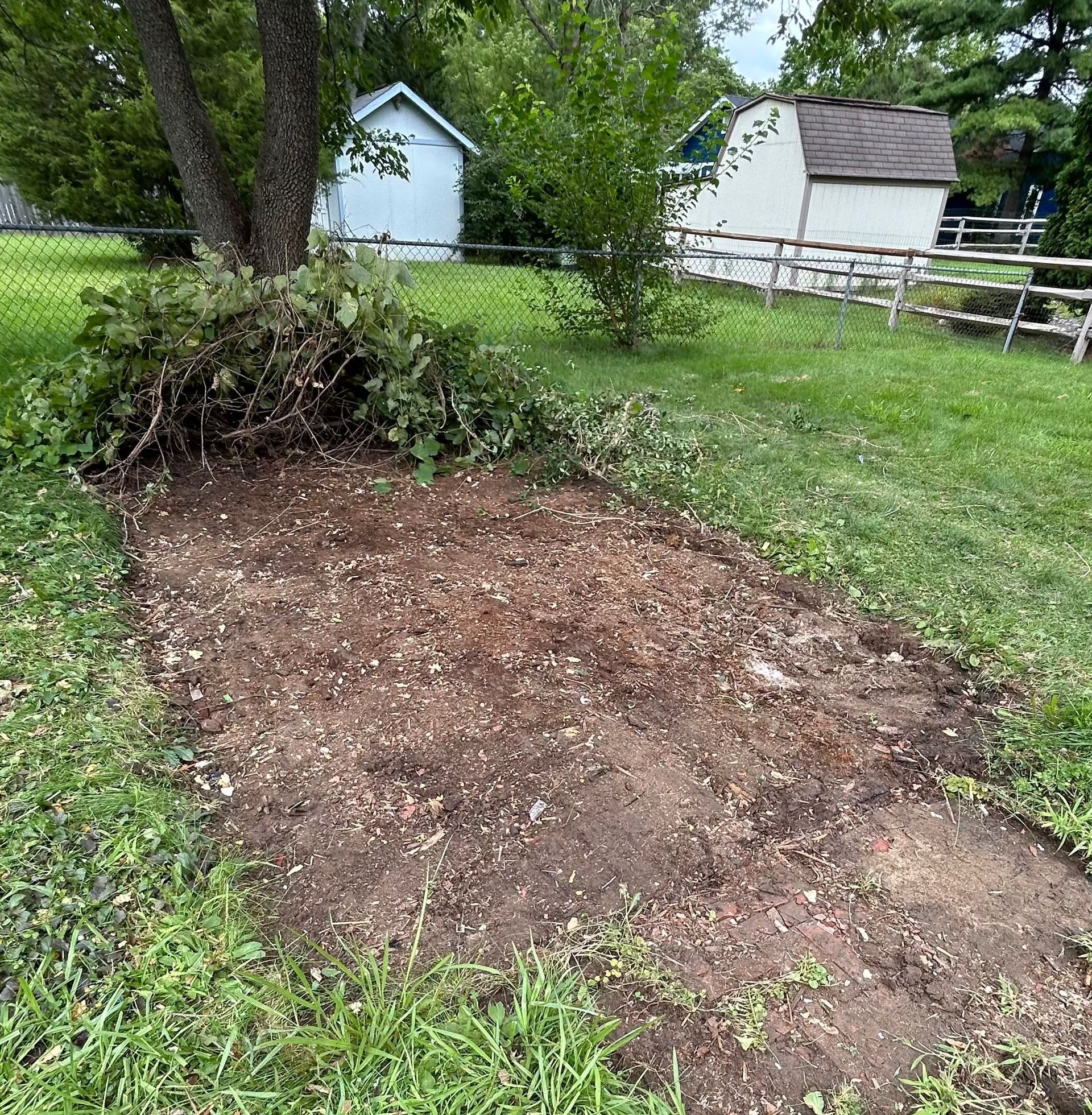There is a pile of dirt in the middle of a grassy field.