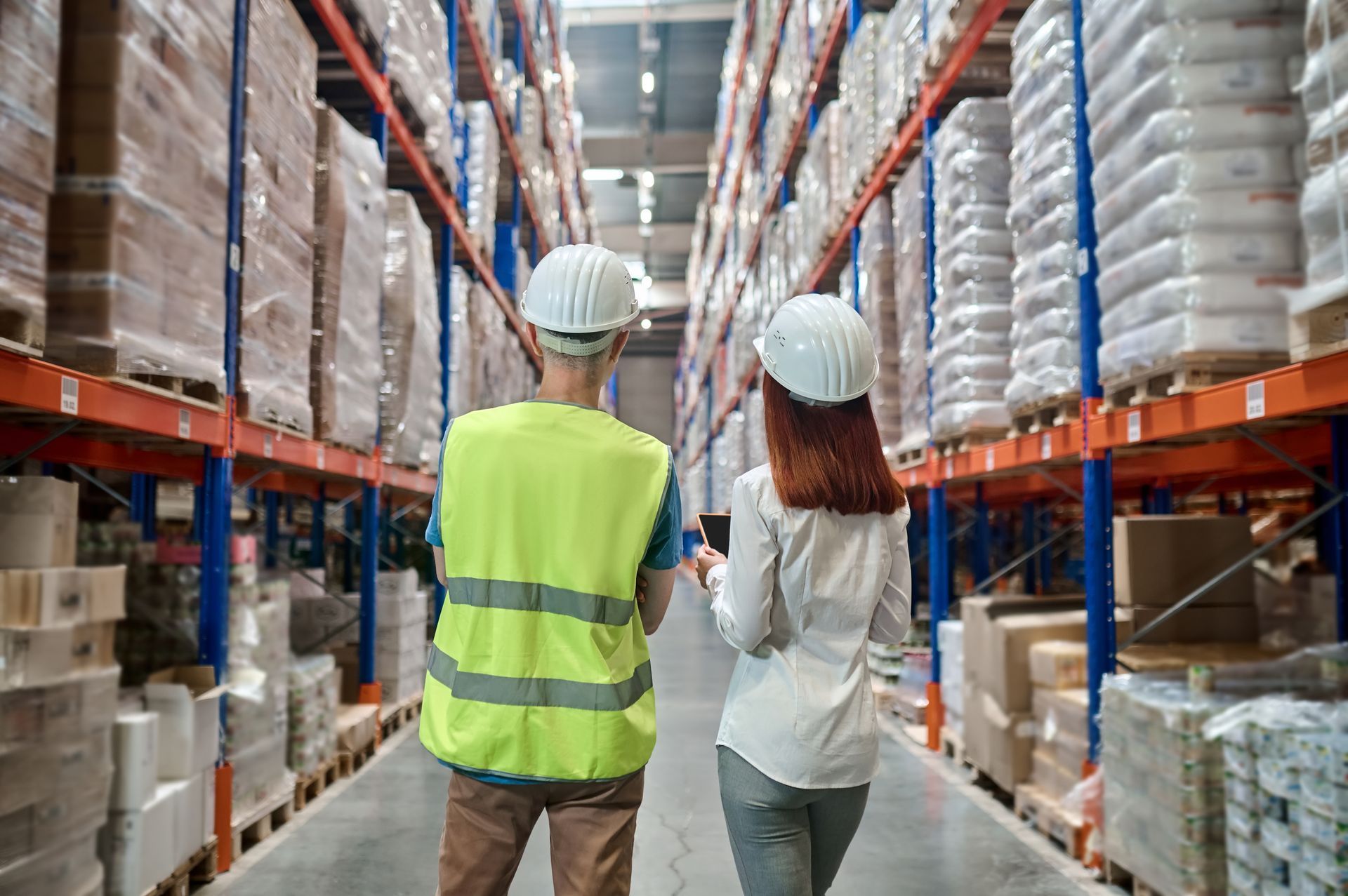 A man and a woman are walking through a warehouse.