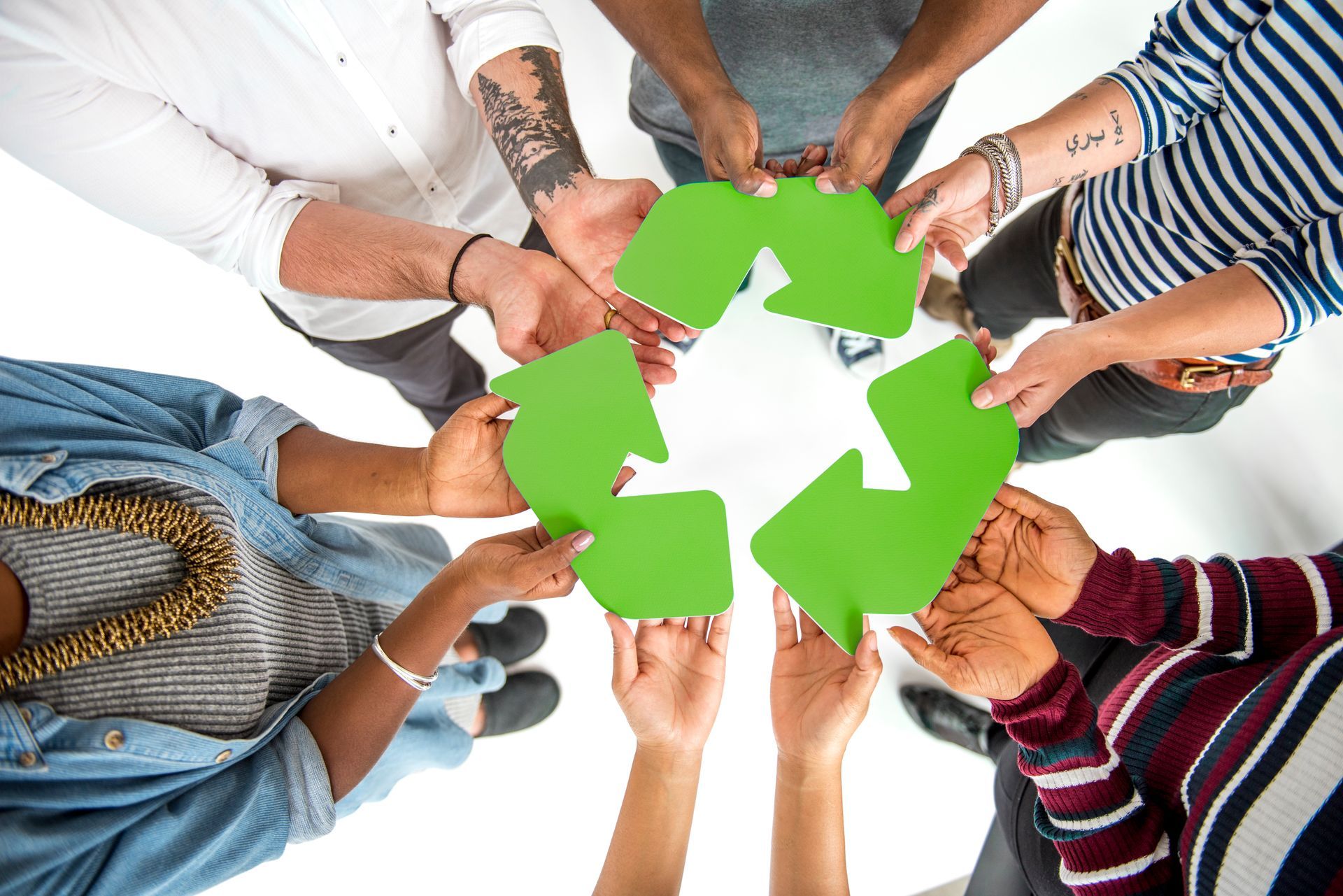 A group of people are holding a green recycling symbol in their hands.