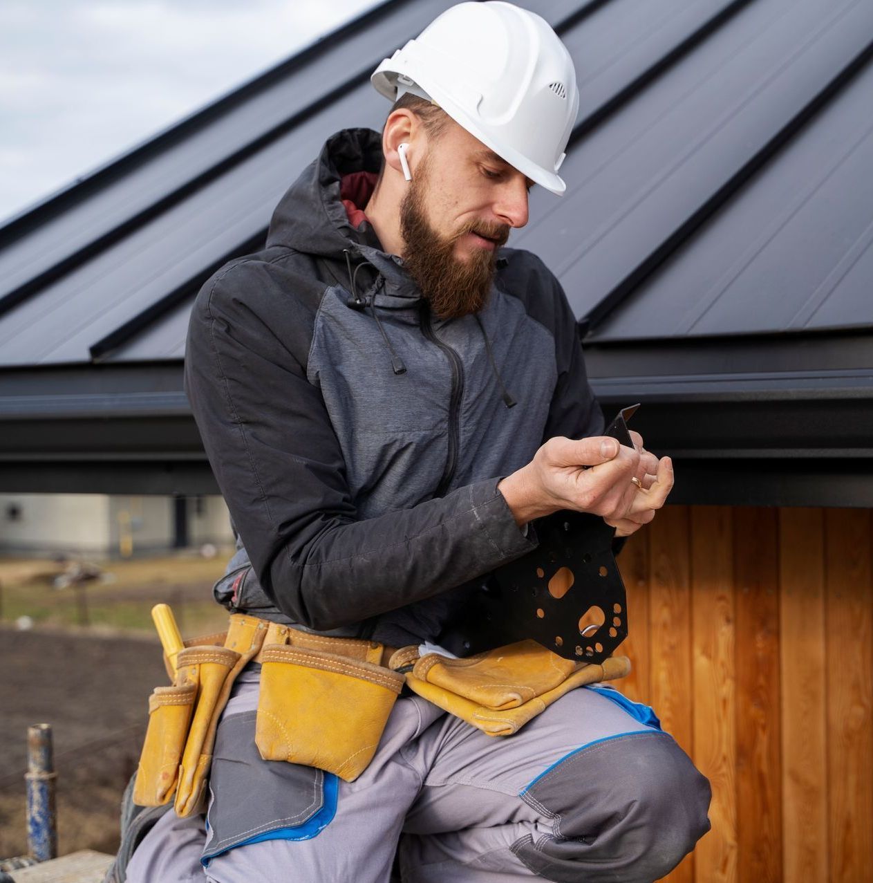 A man wearing a hard hat is looking at his shed dismantling tools