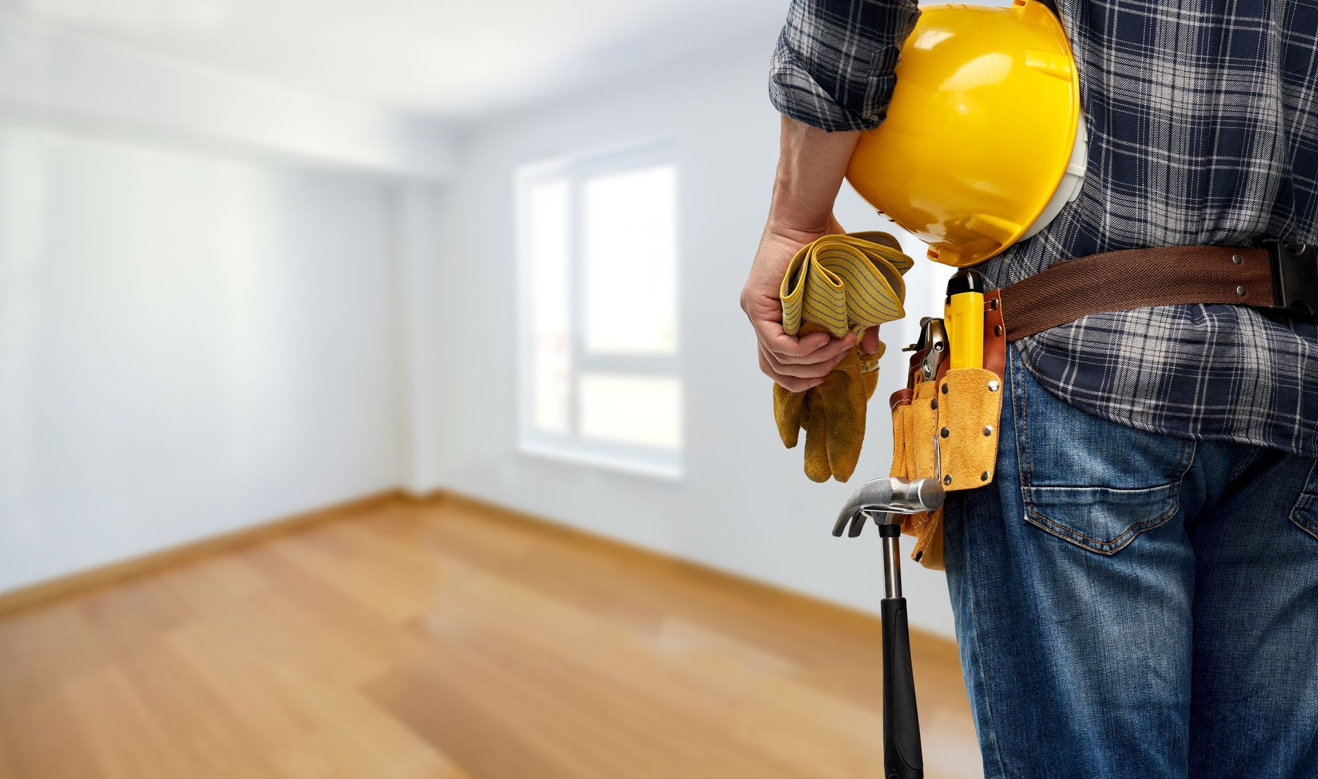 A man wearing a hard hat and overalls is standing with his arms crossed.