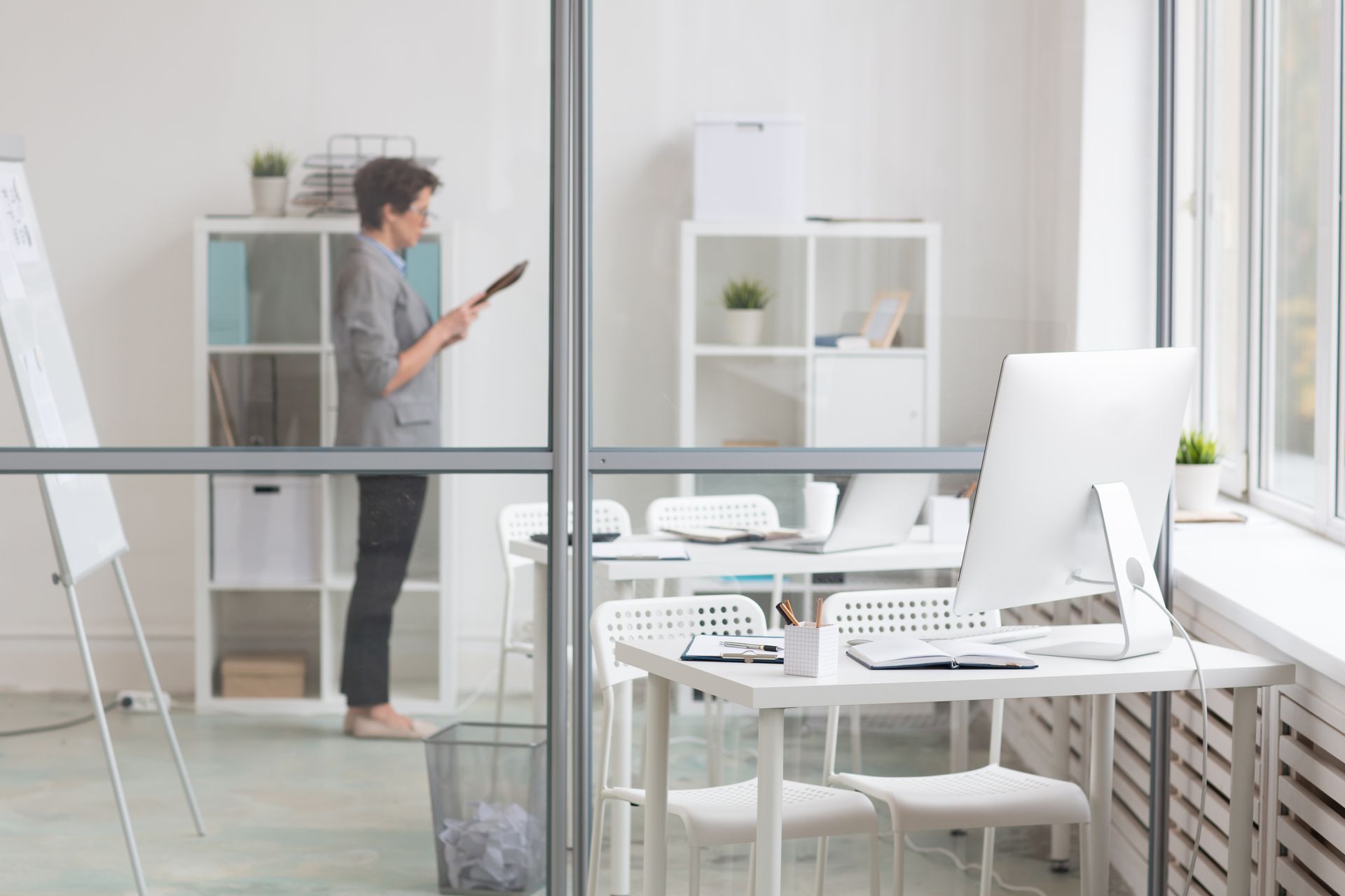 A woman is standing in an office looking at a tablet.