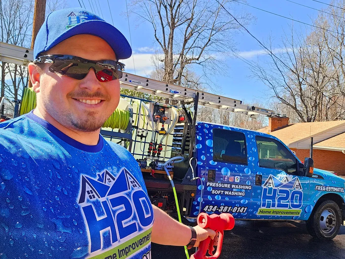 Man in blue H2O shirt and cap posing beside a blue utility truck outdoors on a sunny day