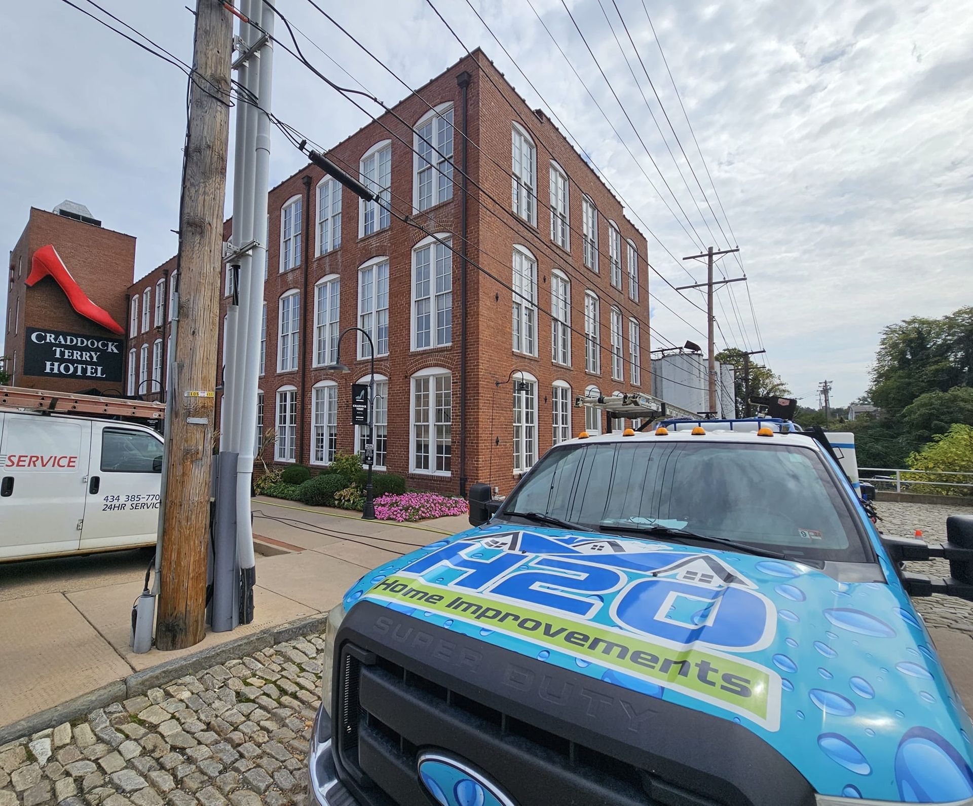 Blue van outside a brick office building on a cobblestone street under cloudy skies