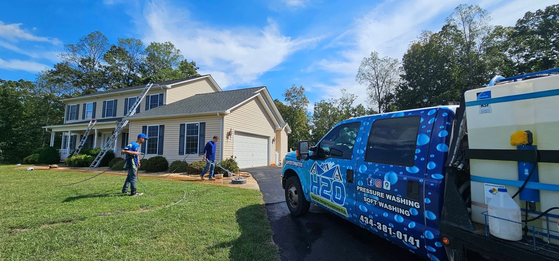 Blue service truck parked outside a beige suburban house under a bright blue sky
