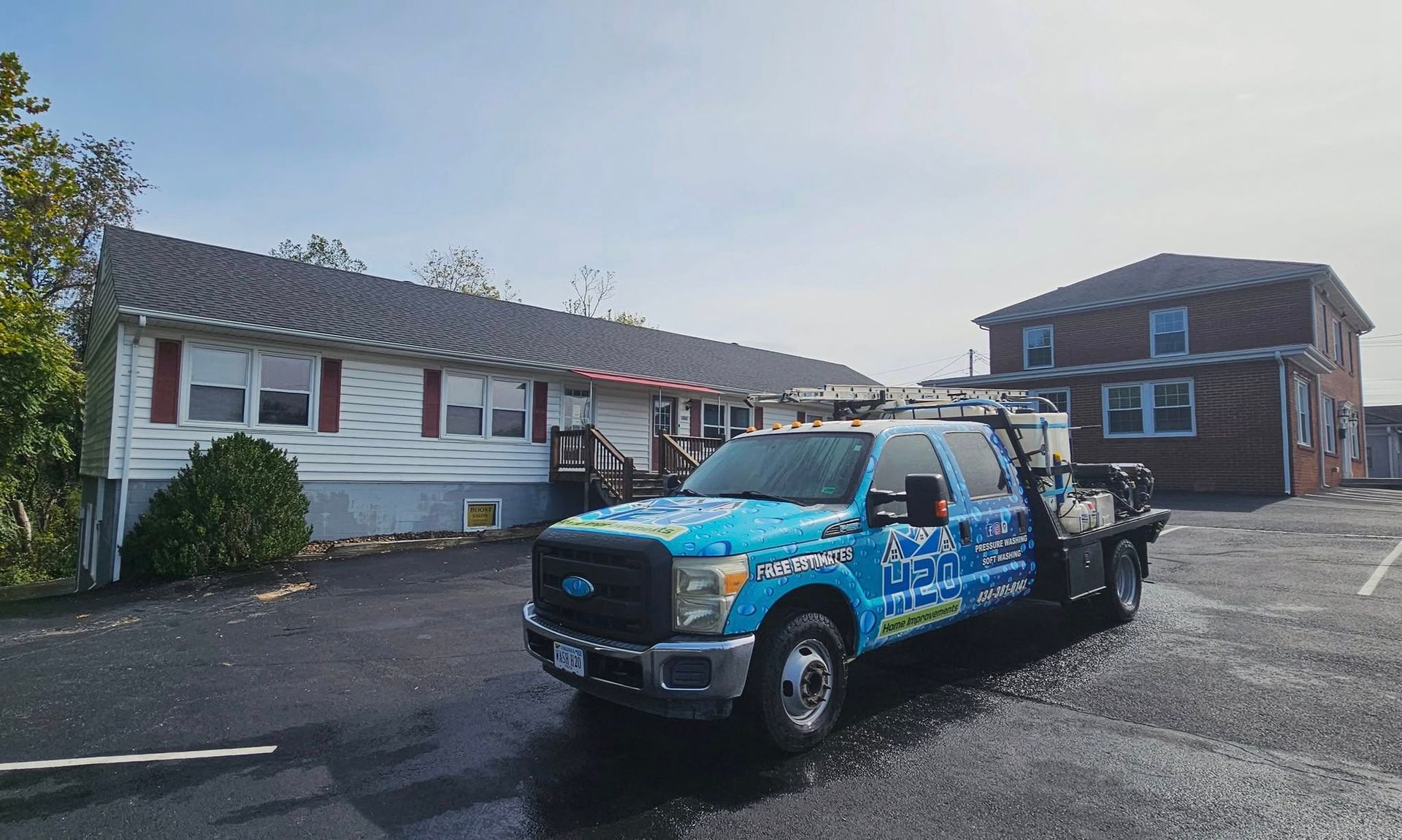 Blue tow truck parked in a motel lot beside a white building at dusk