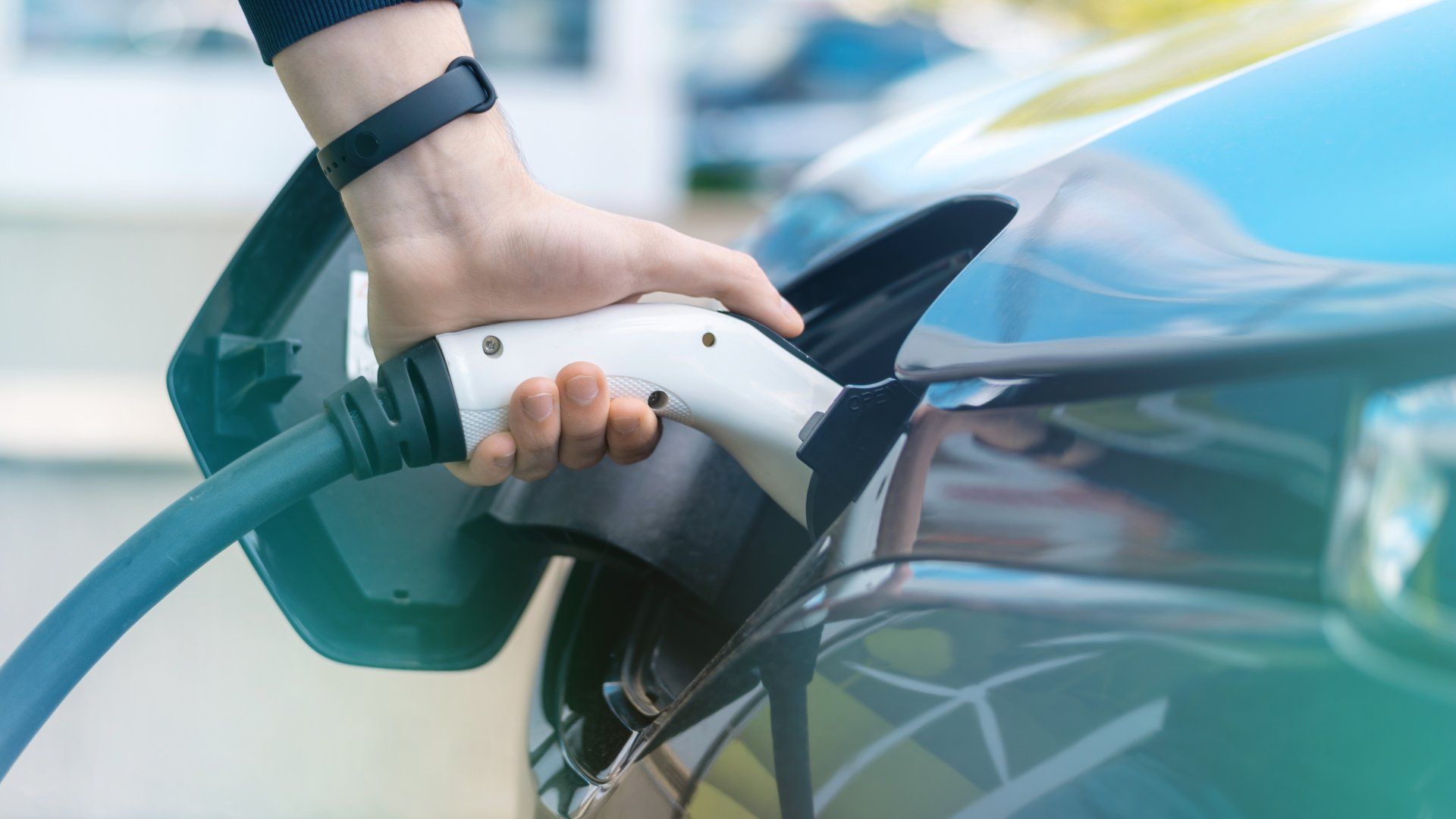 Stock photo of a hand plugging a charger into an Electric Vehicle (EV)