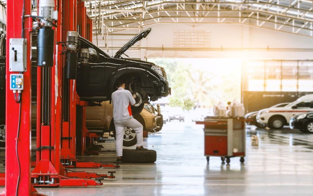 A Man Is Working on A Car in A Garage — Docs Mobile Tyre Service in Hervey Bay, QLD