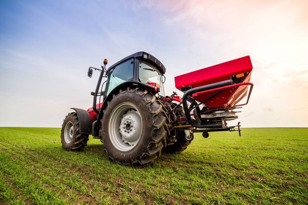 A Tractor Is Spraying Fertilizer on A Lush Green Field — Docs Mobile Tyre Service in Hervey Bay, QLD