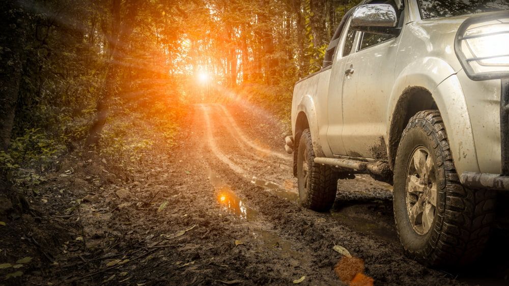 A Truck Is Driving Down a Muddy Road in The Woods — Docs Mobile Tyre Service in Noosa, QLD