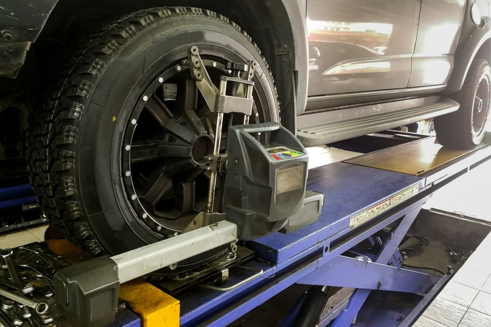 A Car is Being Aligned on a Lift in a Garage — Docs Mobile Tyre Service In Pialba, QLD