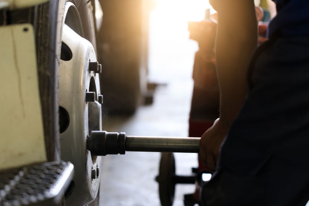 A Man Is Changing a Tire on A Truck with A Wrench — Docs Mobile Tyre Service in Noosa, QLD