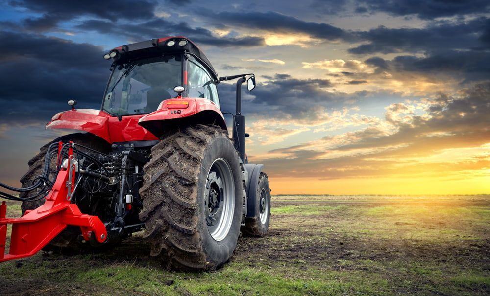 A Red Tractor Is Parked in A Field at Sunset — Docs Mobile Tyre Service in Noosa, QLD