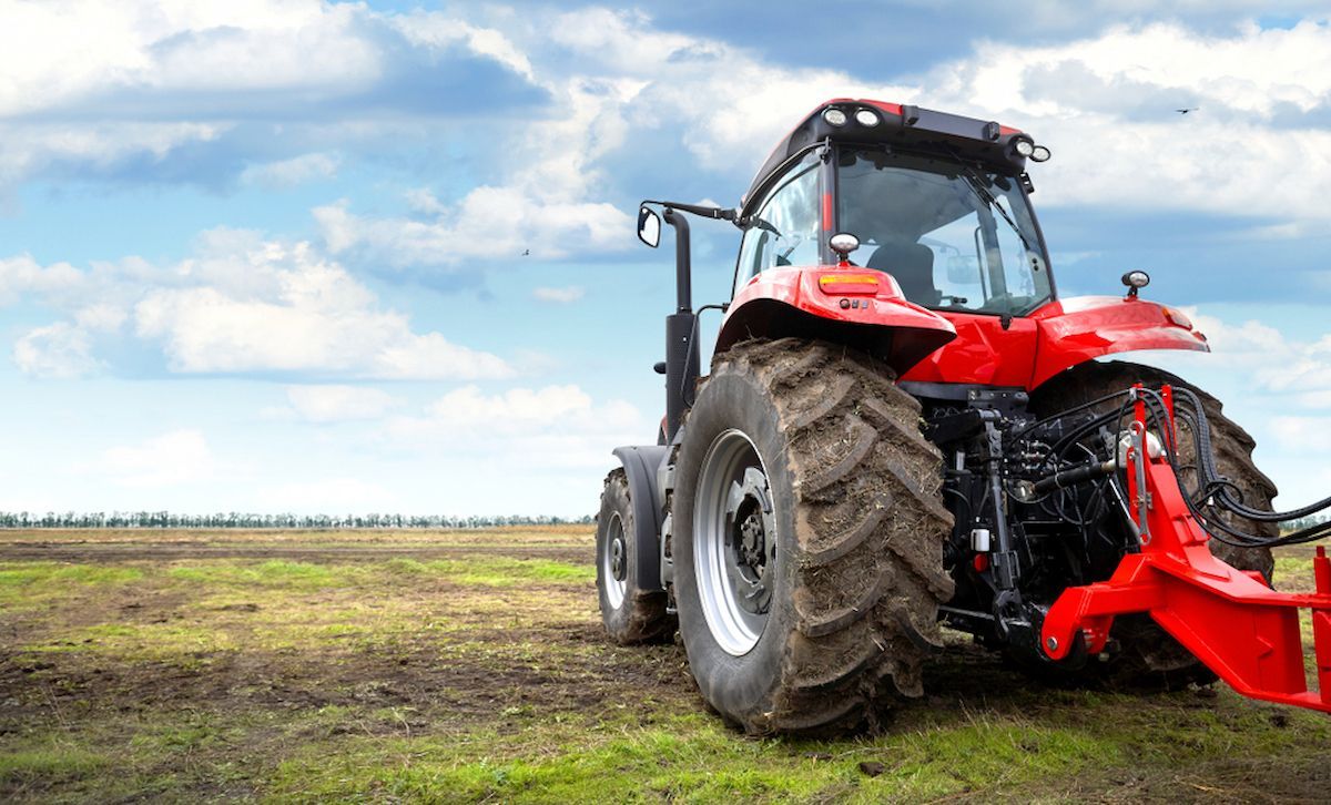 A Red Tractor Is Parked in A Grassy Field — Docs Mobile Tyre Service in Maroochydore, QLD