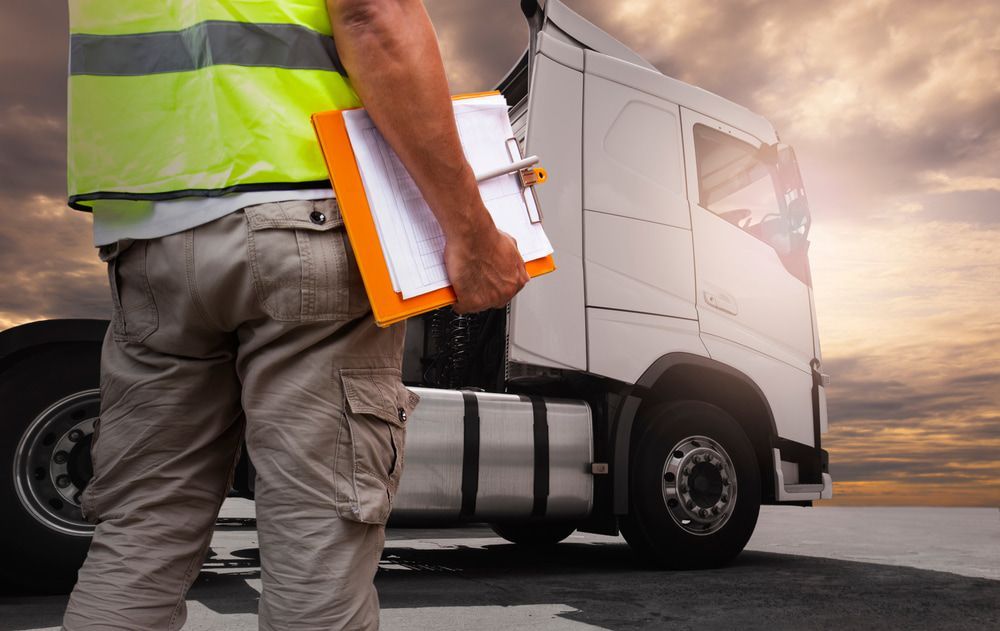 A Man Is Holding a Clipboard in Front of A Truck — Docs Mobile Tyre Service in Noosa, QLD