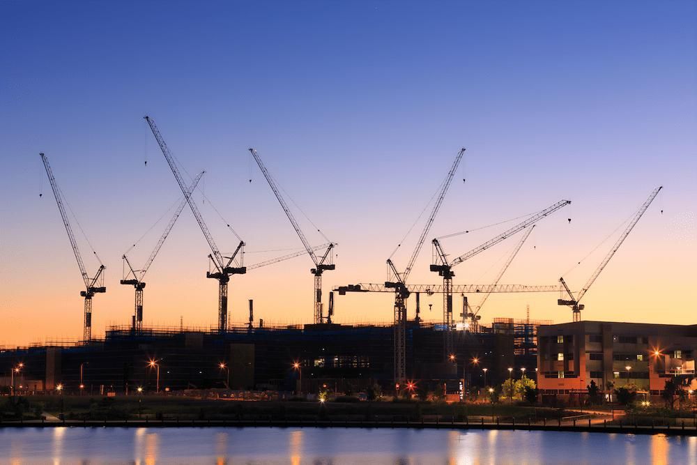 A Row of Cranes Are Sitting Next to a Body of Water at Sunset — Docs Mobile Tyre Service In Kawana, QLD
