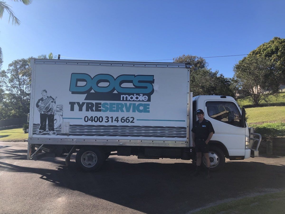 A Man Is Standing Next to A Truck that Says Docs Mobile Tyreservice — Docs Mobile Tyre Service in Hervey Bay, QLD