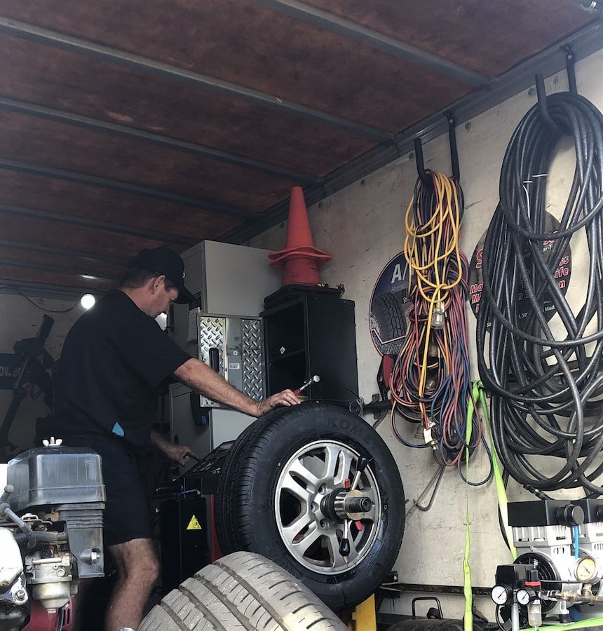A Man Is Working on A Tire in A Garage — Docs Mobile Tyre Service in Hervey Bay, QLD
