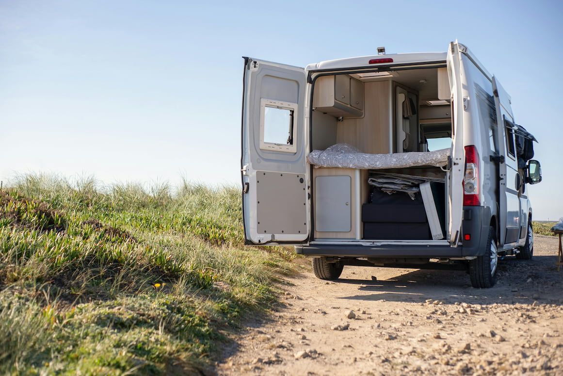 A Camper Van Is Parked on A Dirt Road with Its Doors Open — Docs Mobile Tyre Service in Gympie, QLD