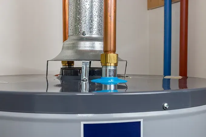 Close-up of a water heater with copper pipes and a brass valve on top